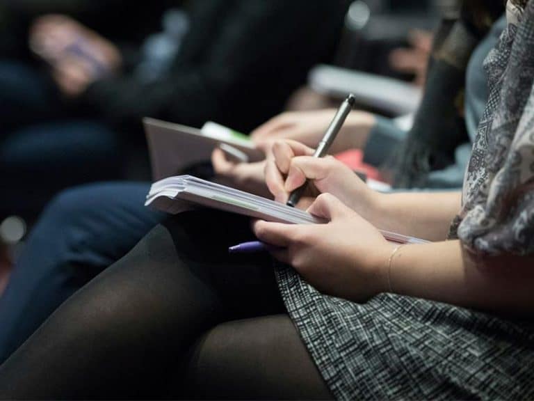 Woman writing notes at conference